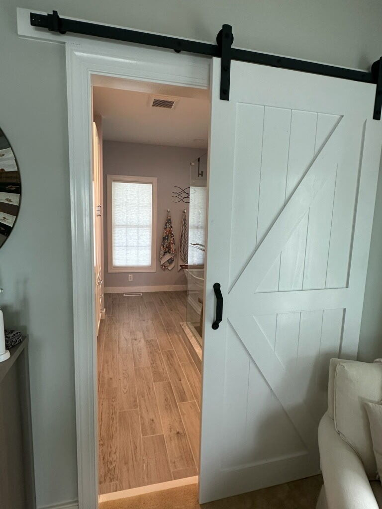 Sliding barn door connecting the primary bedroom to a custom remodeled master bathroom
